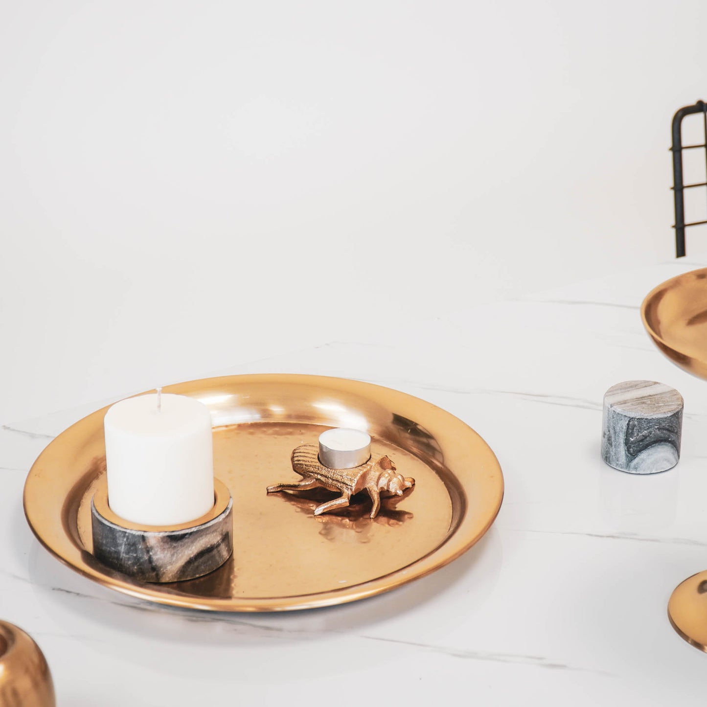 Stompkaarshouder en gouden tor waxinehouder op een gouden dienblad in het midden van een eettafel