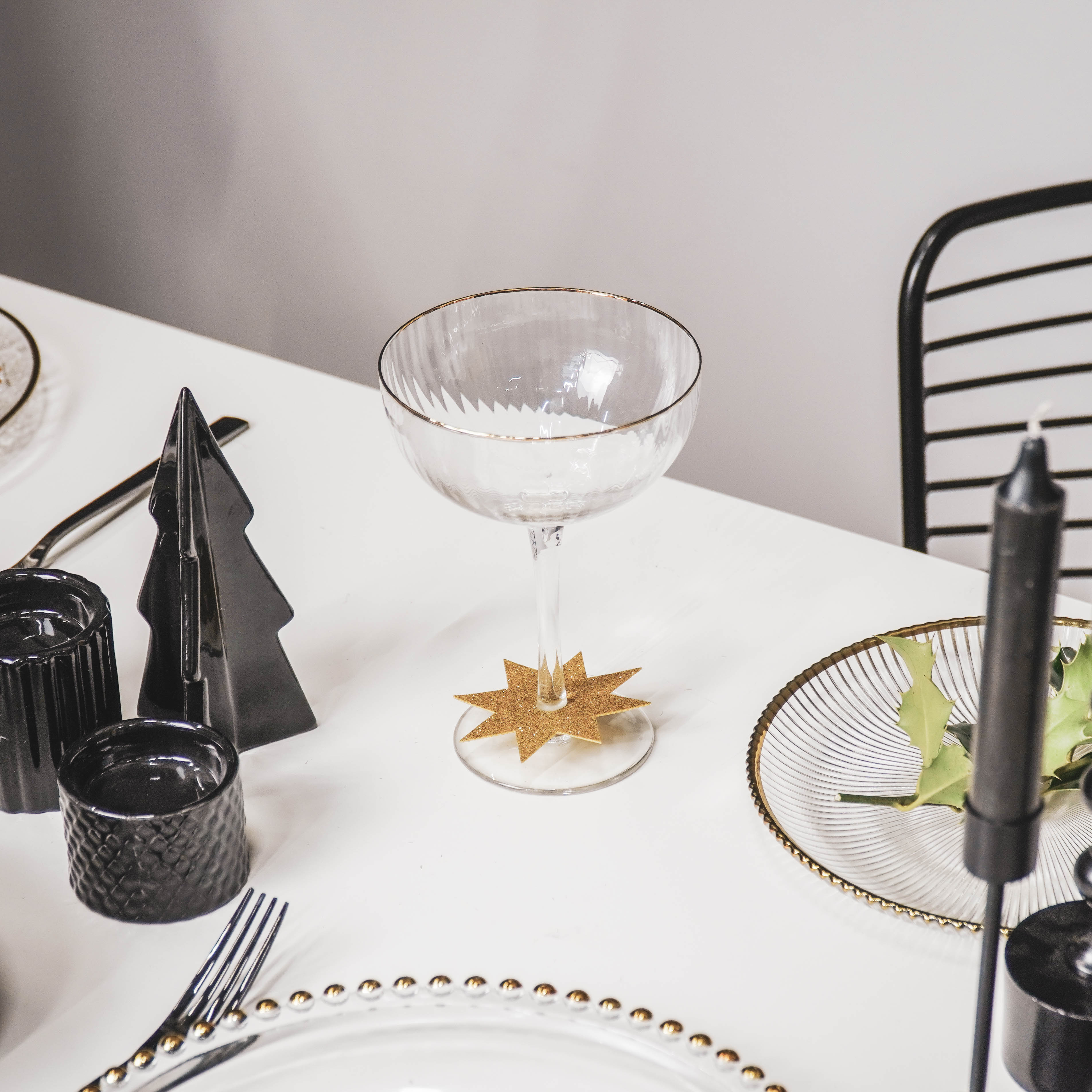 Glazen relief champagneglas op gedekte tafel met glazen borden met gouden randen